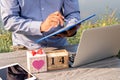 Men use a natural cave laptop with a heart-shaped gift box and wooden calendar. Concept of love, holiday, valentine`s day Royalty Free Stock Photo