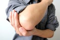 Men use their hands to hold their elbows and He had pain at the elbows.. Painful Health and medical concepts