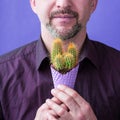 Man with beard with violet ice cream corn with cactus in his hands
