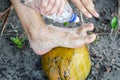 Men is washing his feet with his leg on coco nut at the black sand beach close to ocean.