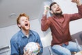 Men watching sport on tv together at home stand up cheering Royalty Free Stock Photo