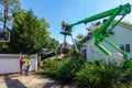 Men wearing hard hats working for a tree service are seen helping to remove a tree that had fallen on the roof of a house