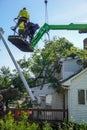 Men wearing hard hats working for a tree service are seen helping to remove a tree that had fallen on the roof of a house