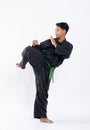 Men wearing pencak silat uniforms with green belts perform defensive leg movements from kicks