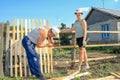 Men and a woman, a daughter with a father, make a picket fence around a summer cottage Royalty Free Stock Photo