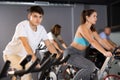 Man and woman taking indoor cycling class at fitness center, doing cardio riding bike Royalty Free Stock Photo