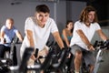 Man and woman taking indoor cycling class at fitness center, doing cardio riding bike Royalty Free Stock Photo