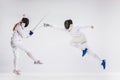 The men and woman wearing fencing suit practicing with sword against gray Royalty Free Stock Photo