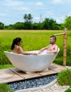 men and women in bath tub outside on vacation at a homestay in Thailand with green rice paddy field Royalty Free Stock Photo