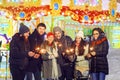 Men and women burning sparklers while standing on Christmas fair