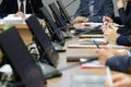 Men and women, businessmen or officials - participants in a meeting in a meeting room. A large table with installed monitors and