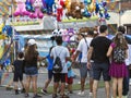 Men, women, and children look at hanging soft toys prizes