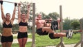 Men and women doing various bodyweight exercises at the horizontal bar