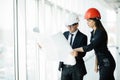 The man and woman in a helmets hold the project plan in the building. Construction business. Royalty Free Stock Photo