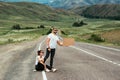 A man and a woman are hitchhiking. Wanderlust, autostop journey concept. Young people traveling hitchhiking. Hitchhiking couple
