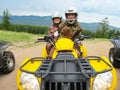 A man and woman of retirement age in camouflage suits and helmets ride a yellow ATV in the mountains. Sports, recreation Royalty Free Stock Photo