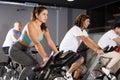 Man and woman taking indoor cycling class at fitness center, doing cardio riding bike Royalty Free Stock Photo