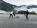 Men and women in their twenties playing a game of spike ball in a mountain parking lot in the Dolomites
