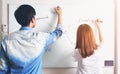 Men and woman are writing a plan on a white board. To present to the team. Royalty Free Stock Photo