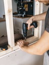 Men work with a screwdriver, fixing a wooden frame for a window in their house. Royalty Free Stock Photo