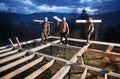 Man worker building wooden frame house on pile foundation.