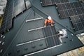 Men workers installing solar panels on roof of house.