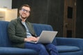 Men working on laptop computer in his room. Home work or study, freelance concept. Young man sitting relaxed on sofa Royalty Free Stock Photo