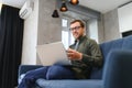 Men working on laptop computer in his room. Home work or study, freelance concept. Young man sitting relaxed on sofa Royalty Free Stock Photo