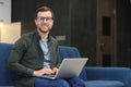 Men working on laptop computer in his room. Home work or study, freelance concept. Young man sitting relaxed on sofa Royalty Free Stock Photo