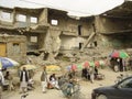 In front of ruined Kabul building, men help illiterate Afghans to write government forms