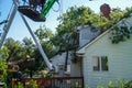 Men working for a tree service are seen helping to remove a tree that had fallen on the roof of a house