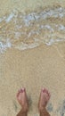 Mens feet, sand, and wave