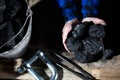 A miner holds small lumps of black coal in his hands over a wooden platform Royalty Free Stock Photo