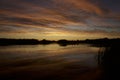 Menacing clouds are colored by the sun at dusk by the lake Royalty Free Stock Photo