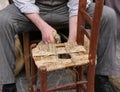 mender of chairs while repairing an old wooden chair with straw