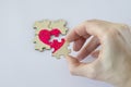 Mending Broken Heart. Woman& x27;s hand assembles a small puzzle from a wooden puzzle with a painted pink heart. Royalty Free Stock Photo