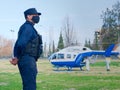 2020-09-06, Mendoza, Argentina - A police officer, wearing a face mask, keeps distance from an emergency services helicopter