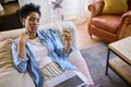 Menopausal Mature Woman At Home With Laptop Having Hot Flush Fanning Herself