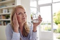 Menopausal Mature Woman At Home Suffering With Headache Pain Drinking Glass Of Water