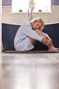 Menopausal Mature Woman Suffering With Incontinence Sitting On Bathroom Floor At Home