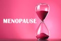 Menopause word and hourglass on pink background