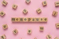 Menopause word on wooden block. Flat lay view on light pink background. Menopause word.