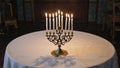 A menorah with lit candles stands on a round table covered with a white tablecloth. The setting is warm and inviting Royalty Free Stock Photo