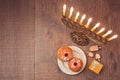 Menorah and sufganiyot on wooden table for Hanukkah celebration. View from above