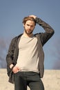 Mens fashion and style. Man with beard in casual wear touch hair on sunny outdoor, fashion. Macho stand on blue sky Royalty Free Stock Photo