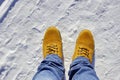 Mens feet in orange boots and jeans in the snow