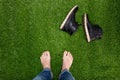 Mens feet resting on green grass with lying boots