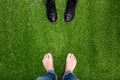 Mens feet resting on green grass standing opposite boots