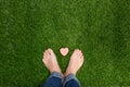 Mens feet standing on grass with small heart