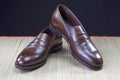 Mens Footwear Concepts. Pair of Stylish Brown Penny Loafer Shoes Placed on Straw Surface against Black.
